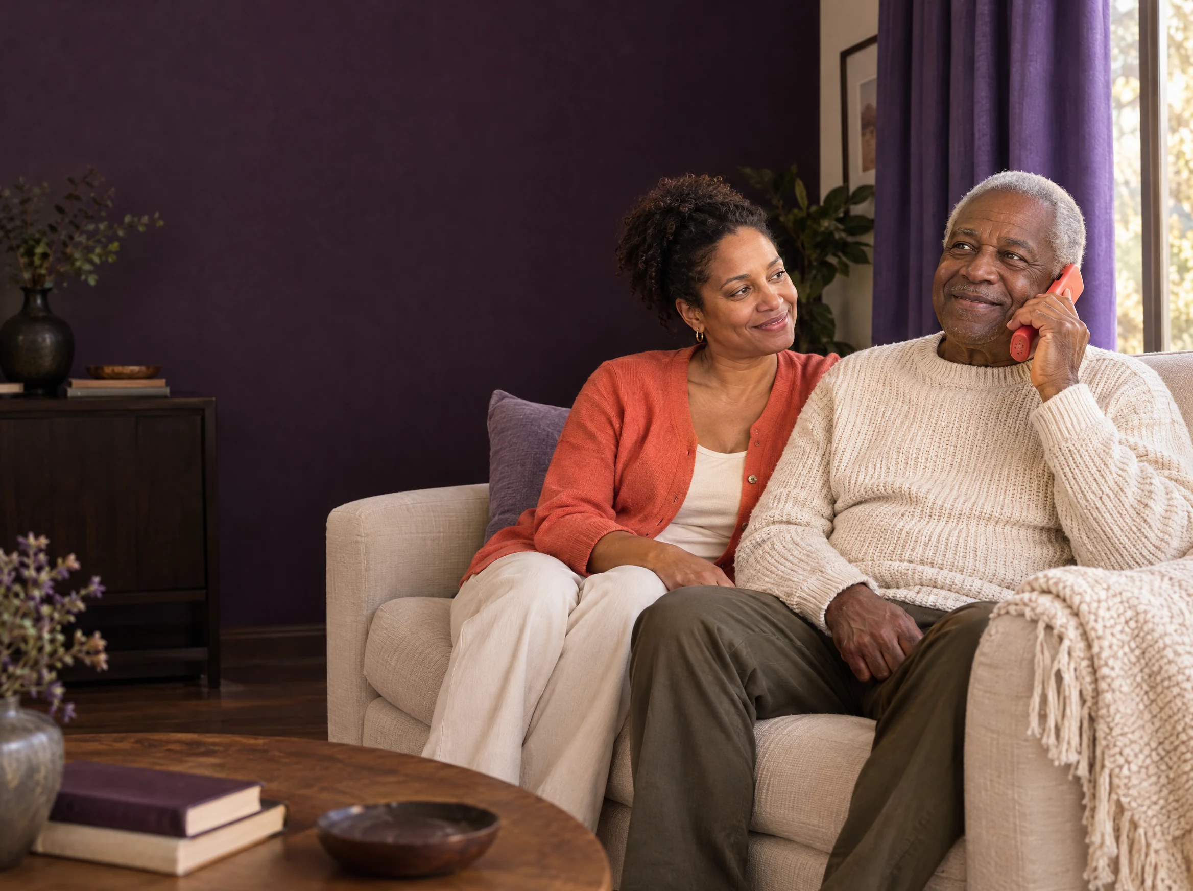 An older man sharing a relaxed phone conversation, with his daughter beside him.